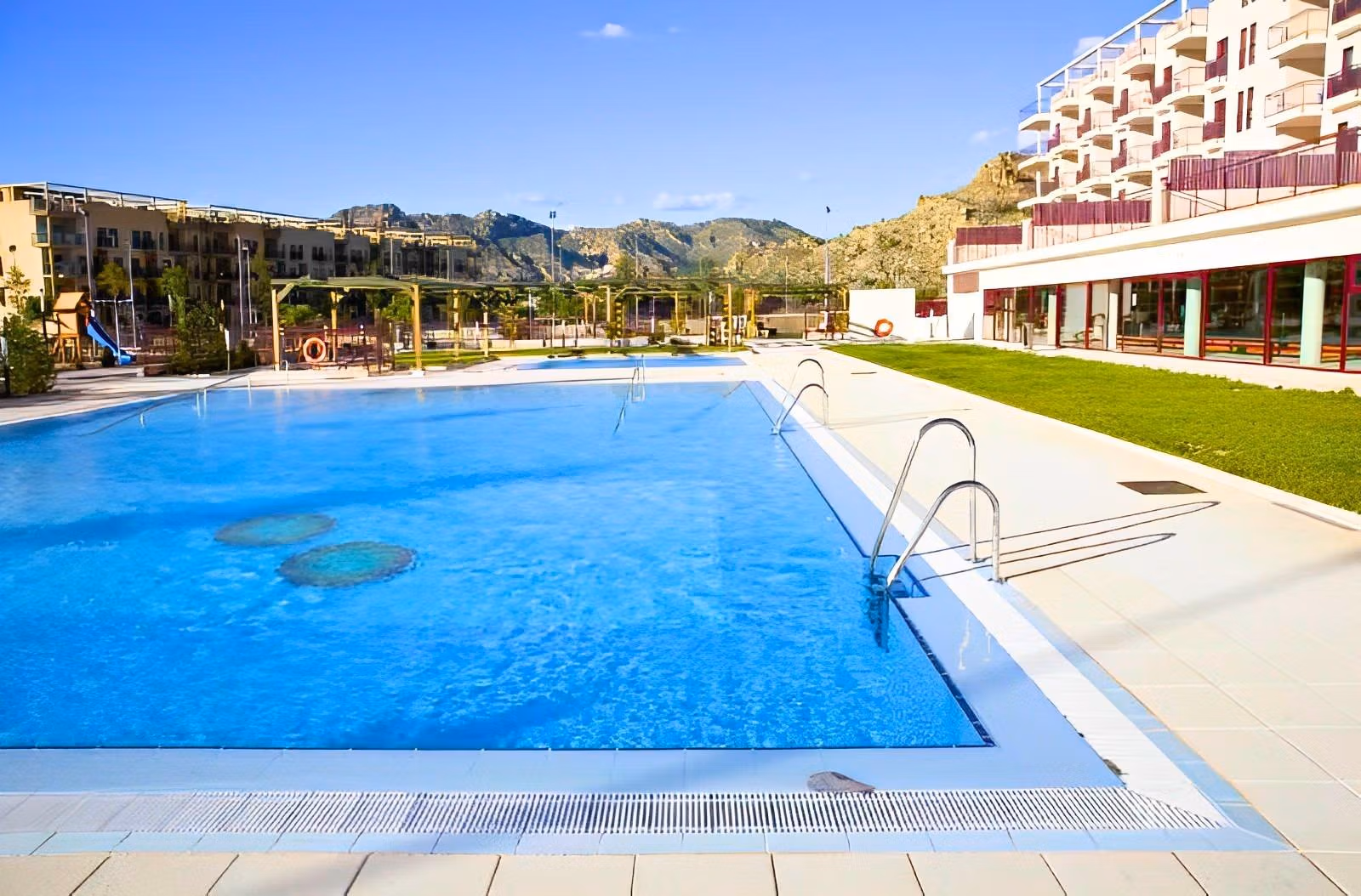 Sun-drenched pool area with modern loungers and landscaped gardens in a charming 1-bedroom apartment complex in Villanueva del Rio Segura near Archena