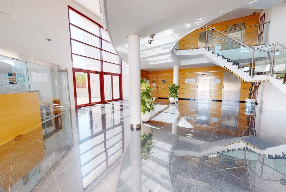Bright, modern lobby with sleek glass staircase and polished floors in a charming 1-bedroom apartment building in Villanueva del Rio Segura.