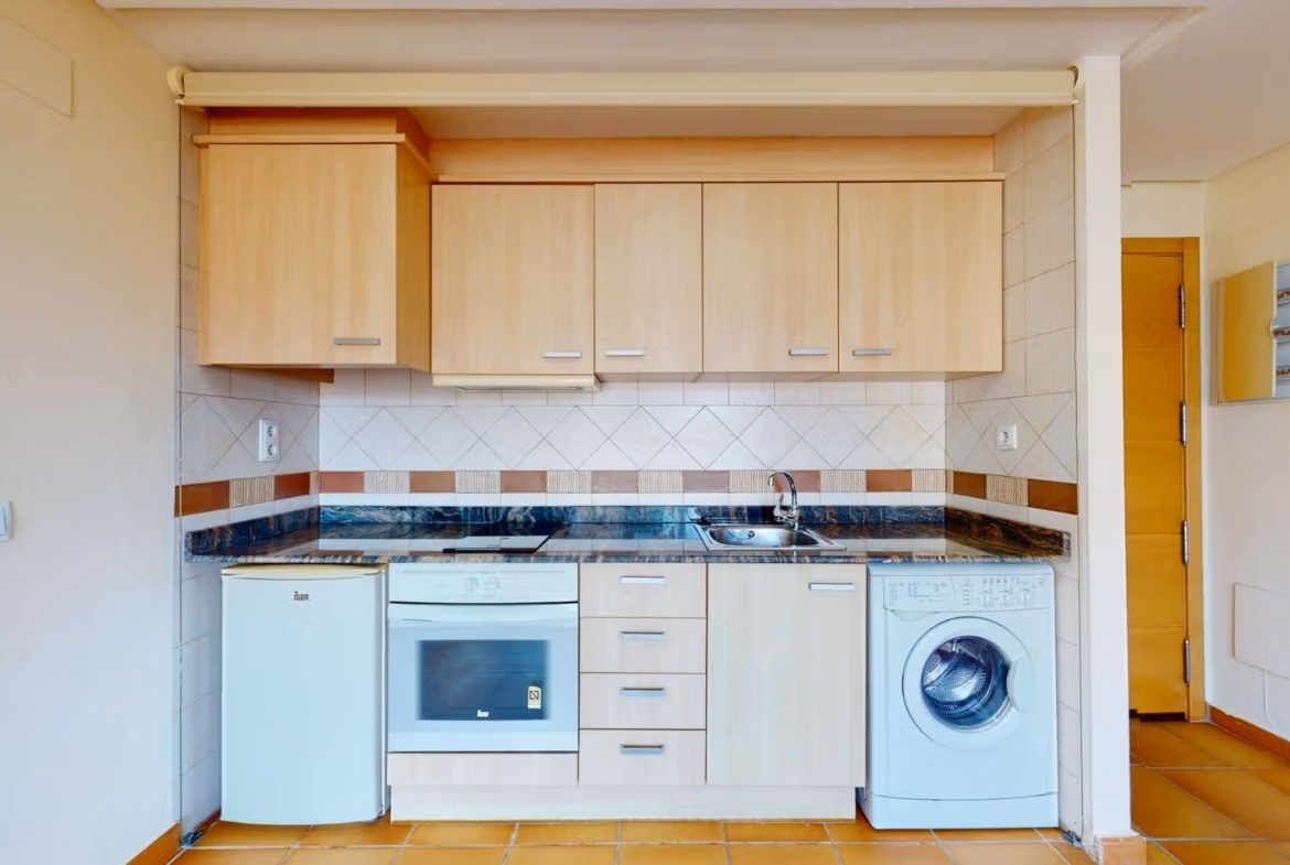 Bright, modern kitchen in a 2-bedroom penthouse near Archena, Murcia, featuring sleek cabinetry and compact appliances.