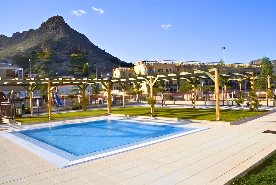 Bright, modern penthouse complex near Archena, Murcia featuring a pristine pool and scenic mountain backdrop under a clear blue sky.