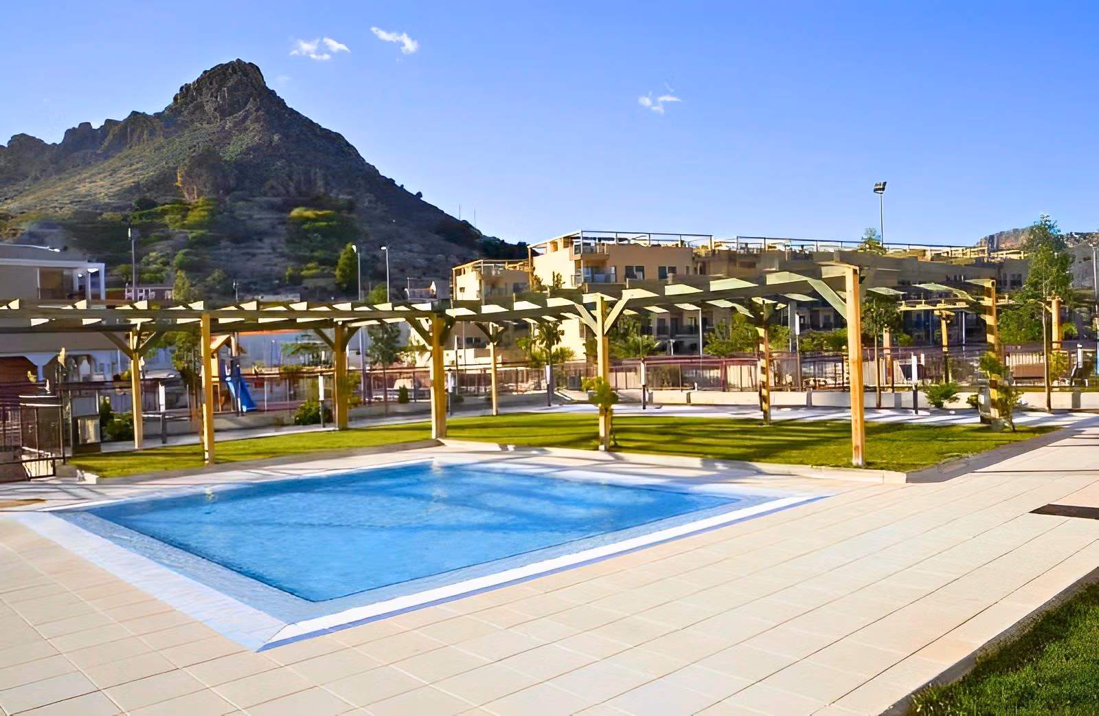 Bright, modern penthouse complex near Archena, Murcia featuring a pristine pool and scenic mountain backdrop under a clear blue sky.