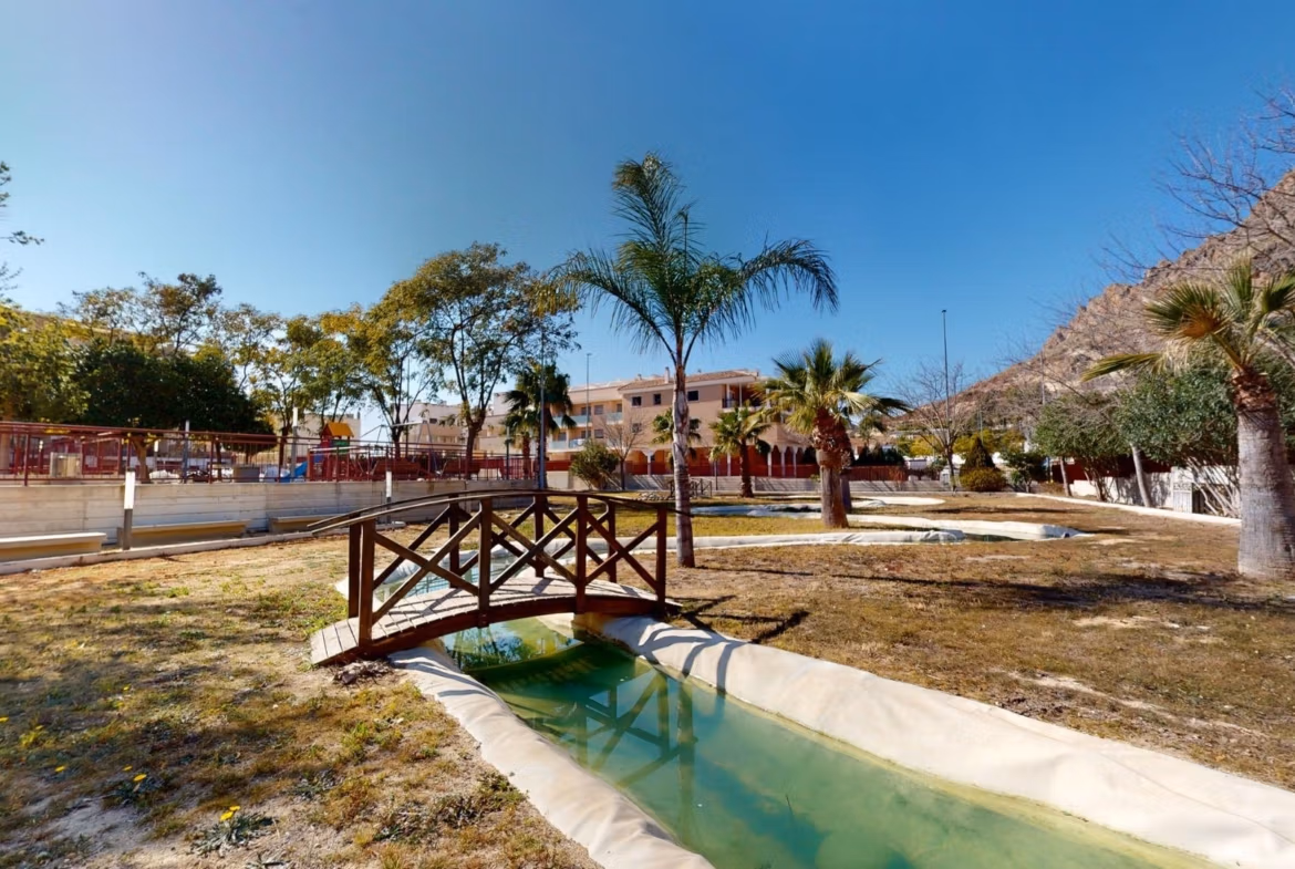 Sun-drenched landscaped garden with charming wooden bridge at 1-bedroom apartment in Villanueva del Rio Segura near Archena