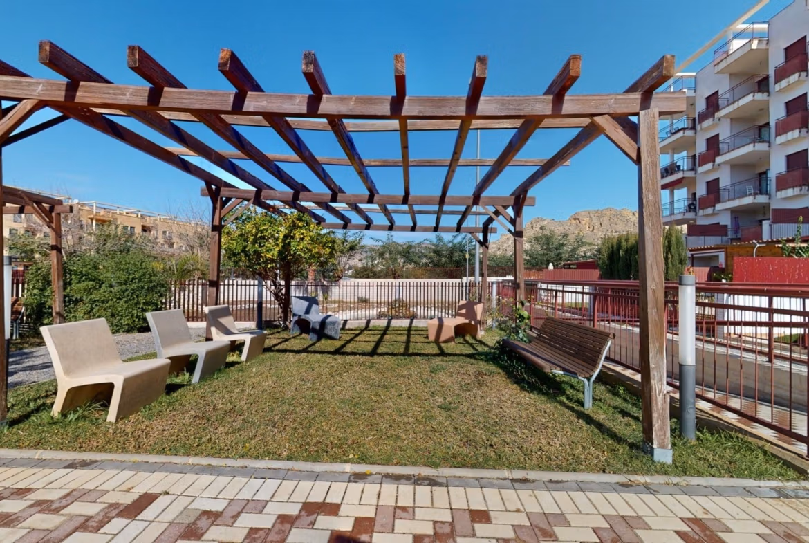 Sun-drenched landscaped terrace with wooden pergola and seating area at luxury 2-bedroom penthouse near Archena, Murcia