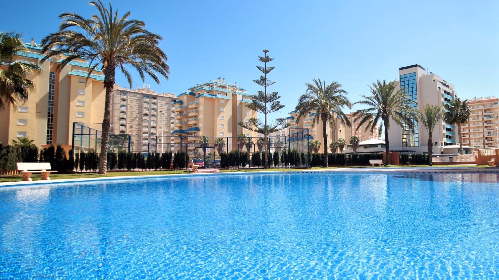 BEAUTIFUL-TOWNHOUSES-IN-LA-MANGA-15 Sparkling communal pool with palm trees and modern buildings surrounding a bright new build 2-bedroom townhouse in La Manga del Mar Menor.