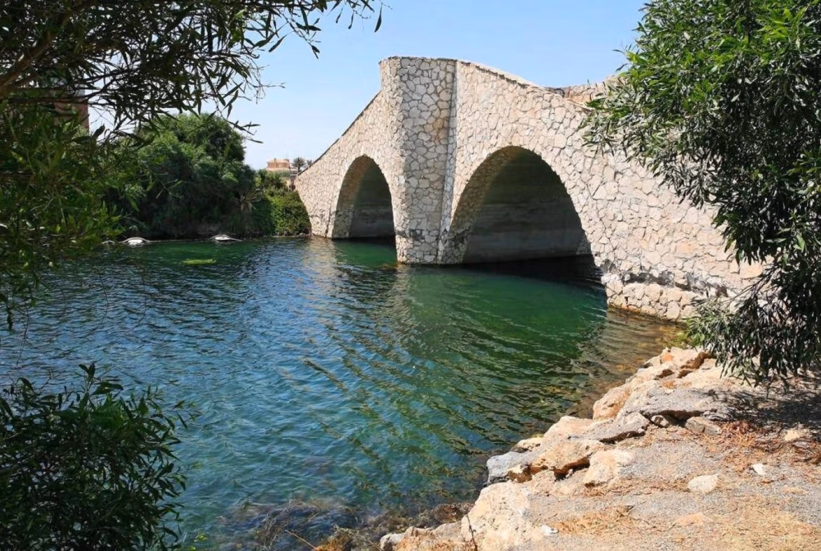 Serene stone bridge over crystal-clear water surrounded by lush greenery near luxury 2-bedroom townhouse in La Manga del Mar Menor
