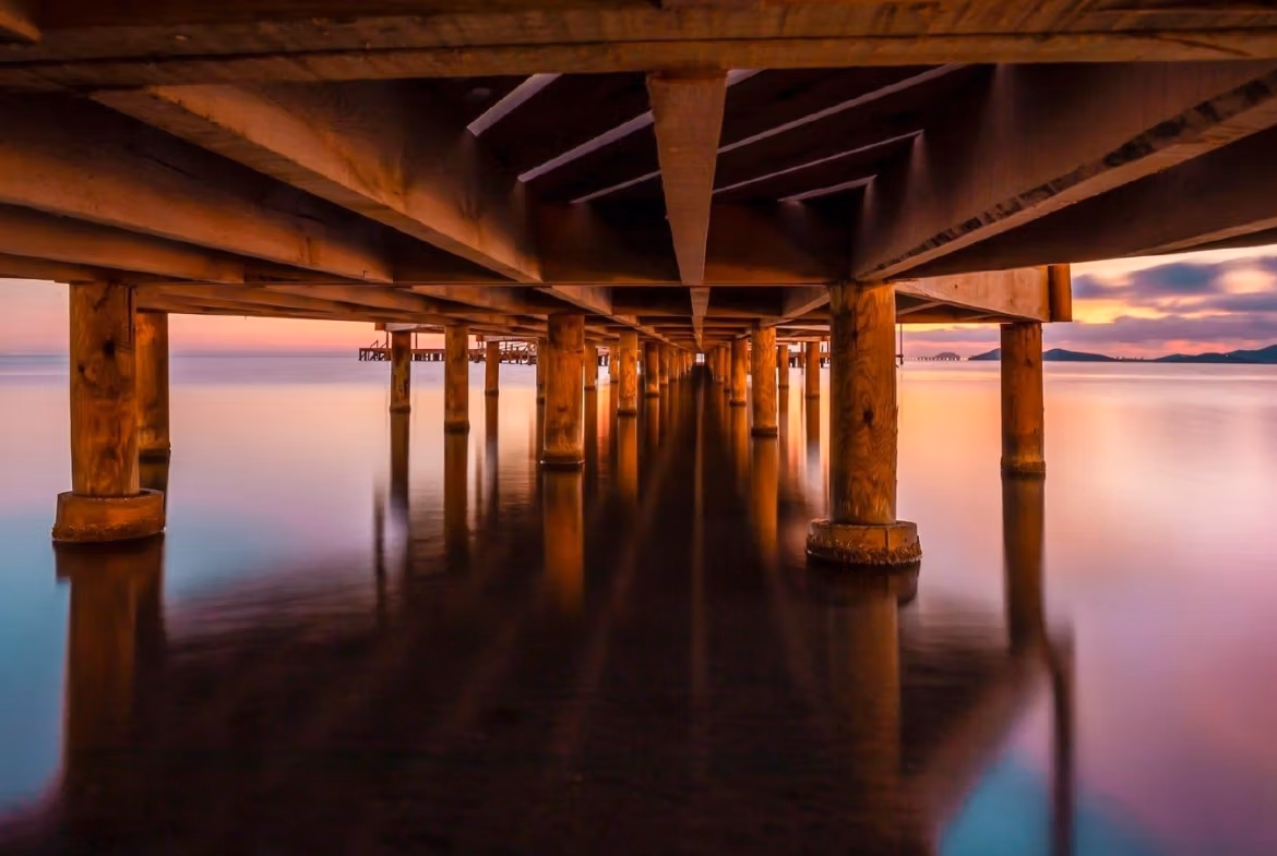 Serene sunset view under wooden pier with calm sea waters near spacious new build townhouse in La Manga del Mar Menor