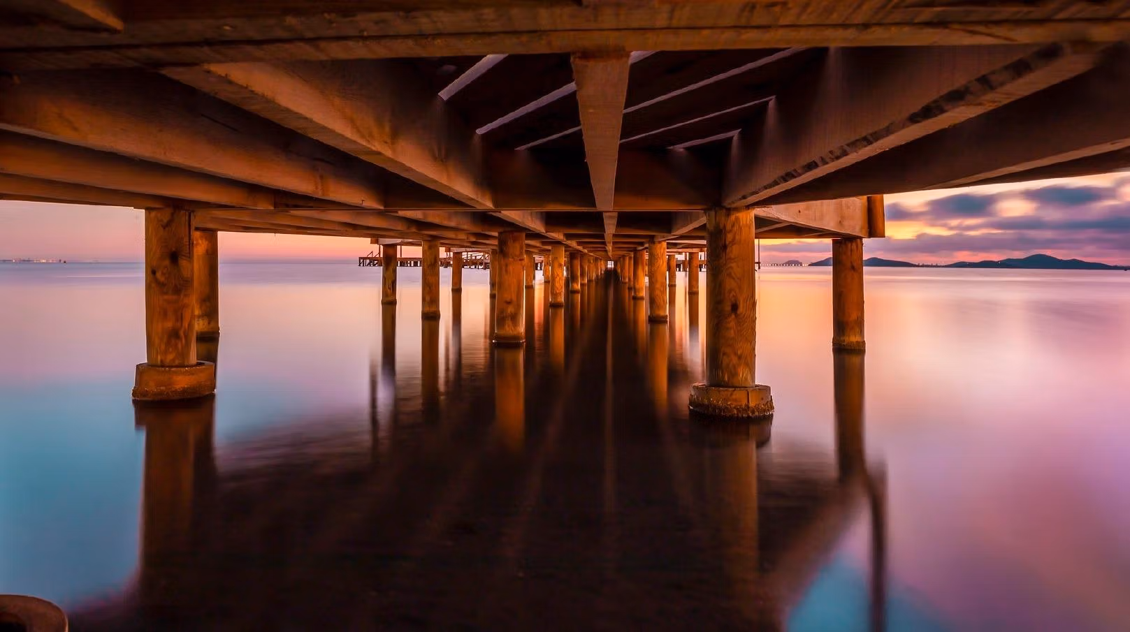 BEAUTIFUL-TOWNHOUSES-IN-LA-MANGA-18 Serene sunset view under wooden pier with calm sea waters near spacious new build townhouse in La Manga del Mar Menor