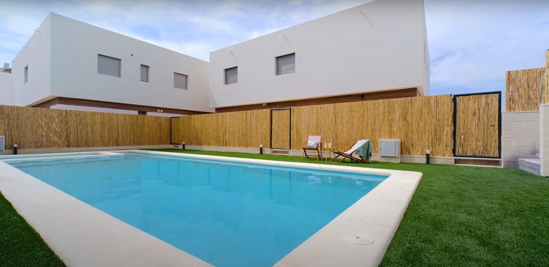 Modern new build 3-bedroom property in Orihuela Costa featuring a pristine communal pool and stylish exterior near the beach.
