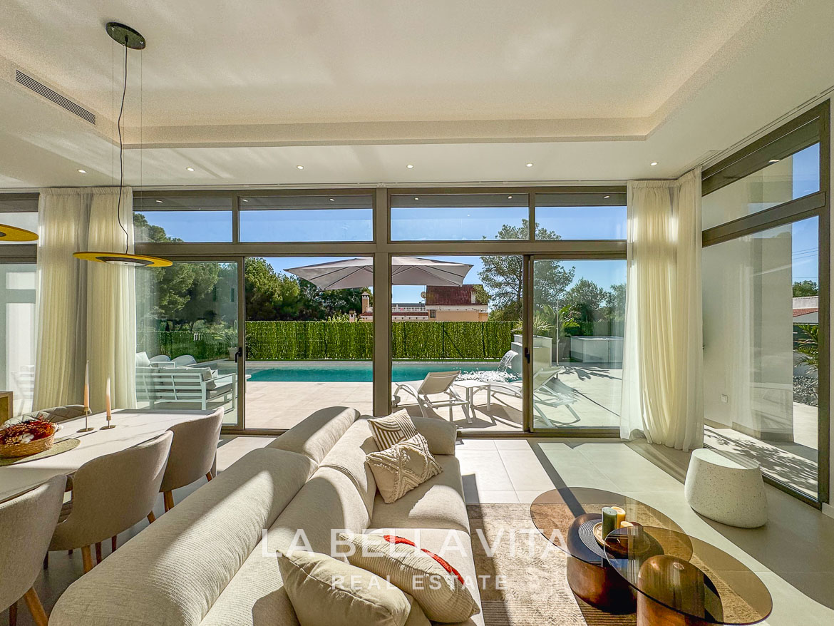Sun-drenched open-plan living area with modern furnishings and glass doors opening to a private pool in 3-bedroom villa, Pinar de Campoverde