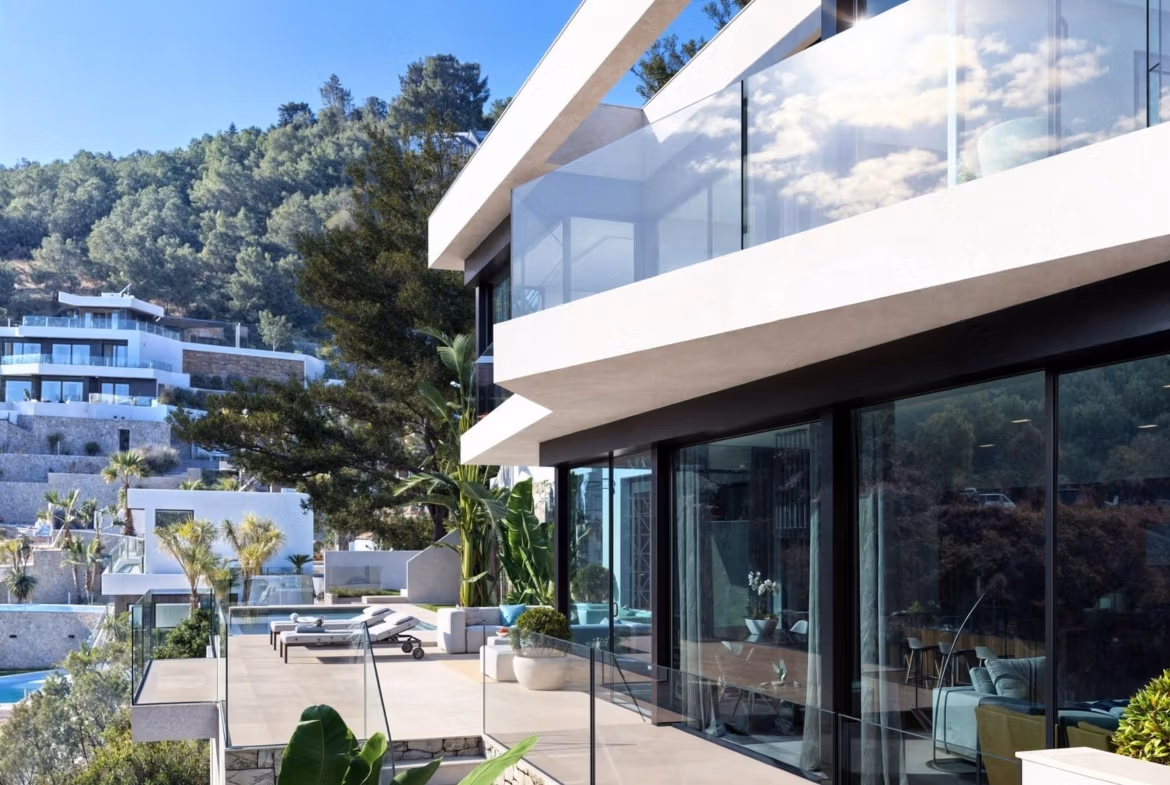 Modern 4-bedroom villa in Benissa Costa with sleek glass terraces, lush landscaping, and panoramic sea and hillside views.