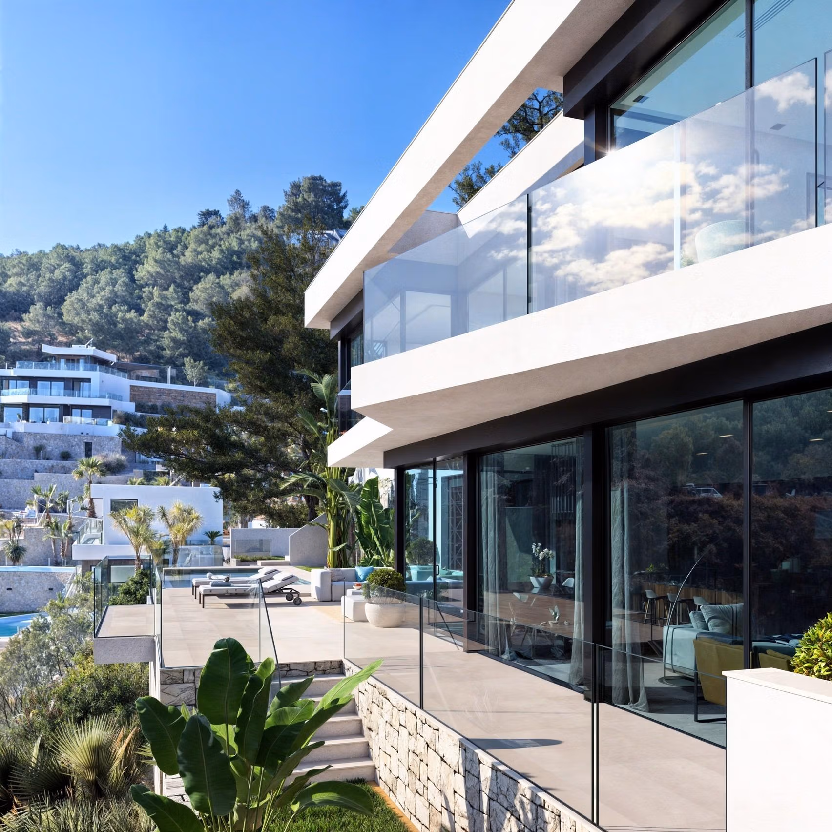 Modern 4-bedroom villa in Benissa Costa with sleek glass terraces, lush landscaping, and panoramic sea and hillside views.