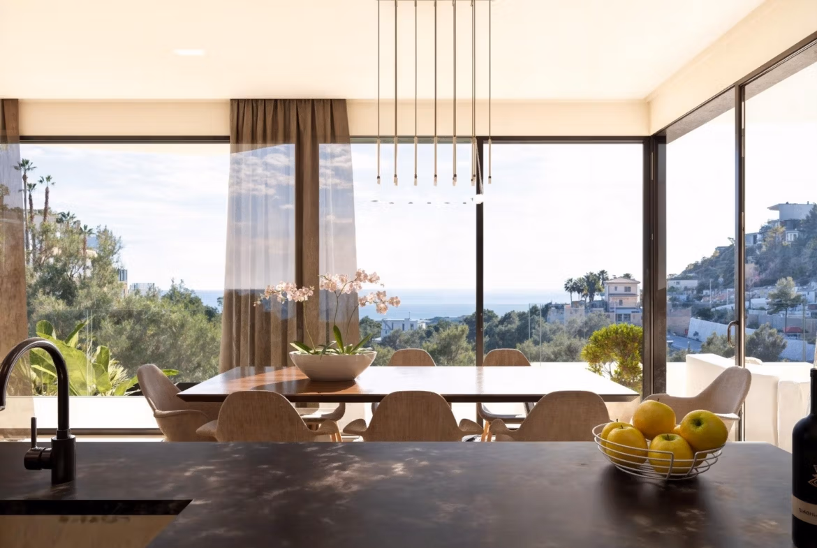 Bright modern dining area with panoramic sea views and floor-to-ceiling windows in luxury 4-bedroom villa in Benissa Costa.