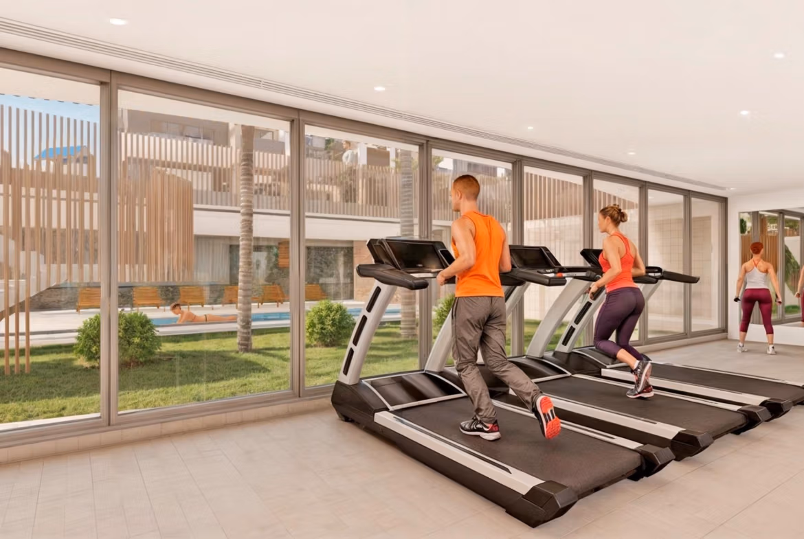 Bright modern gym with floor-to-ceiling windows in exclusive Torre de la Horadada penthouse complex, offering serene outdoor views.