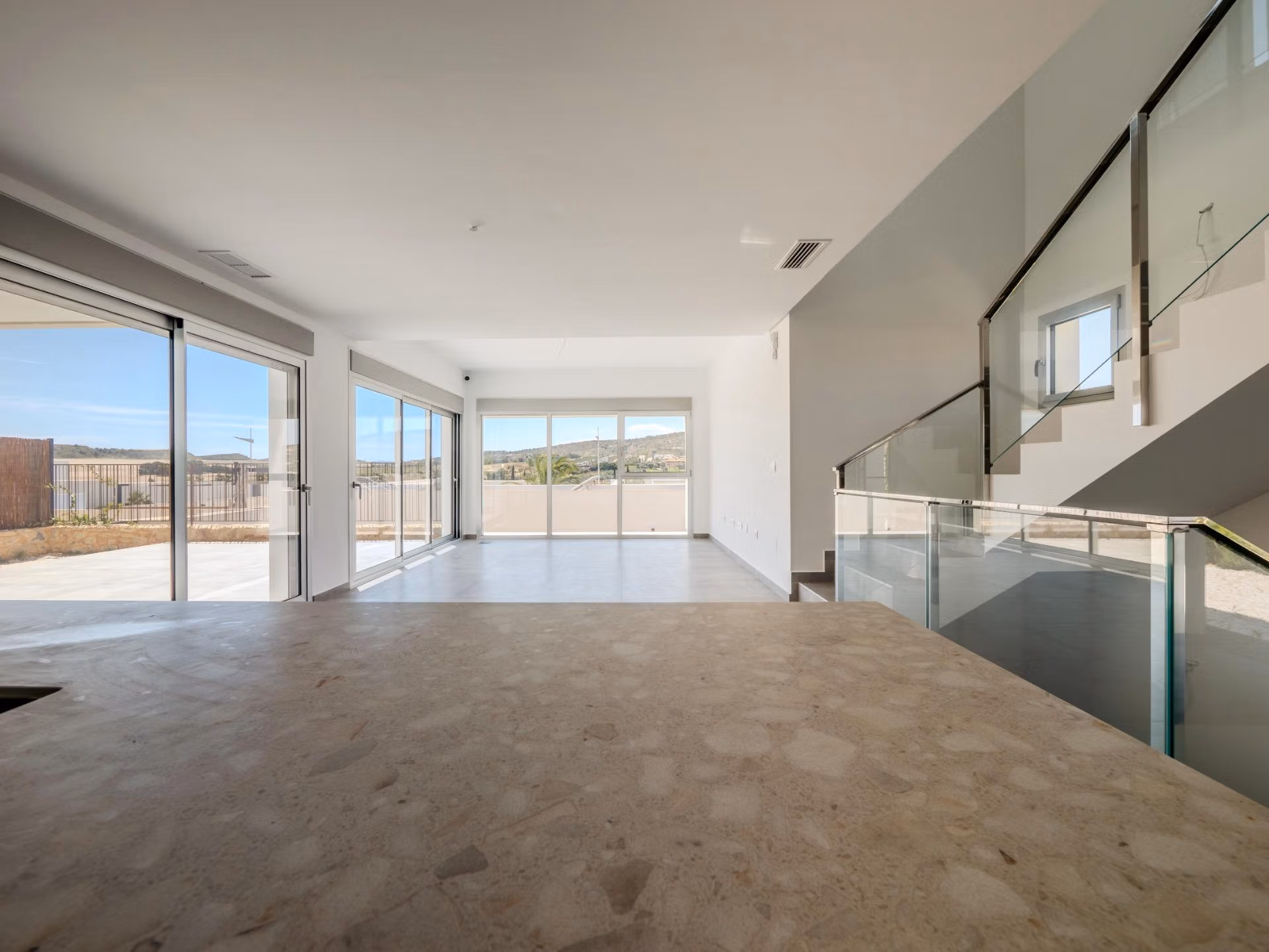 Bright open-plan living area with floor-to-ceiling windows showcasing panoramic golf views in a modern 4-bedroom villa in Algorfa, La Finca.