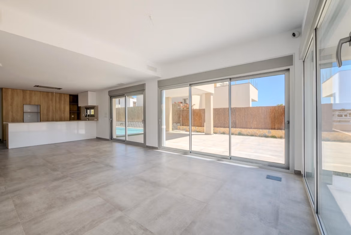 Bright open-plan living area with sleek kitchen and expansive glass doors in a modern 4-bedroom villa in Algorfa, La Finca.