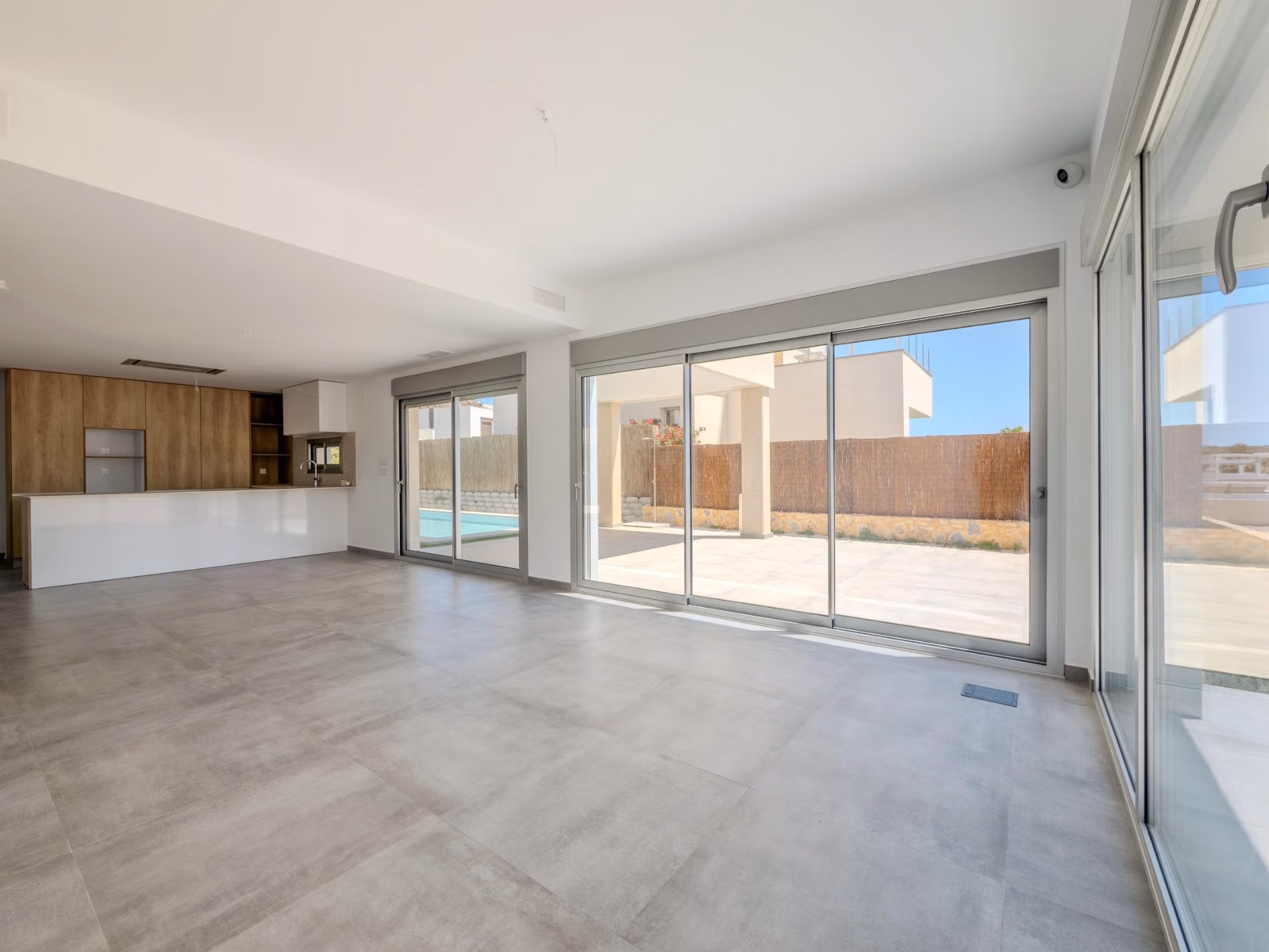 Bright open-plan living area with sleek kitchen and expansive glass doors in a modern 4-bedroom villa in Algorfa, La Finca.