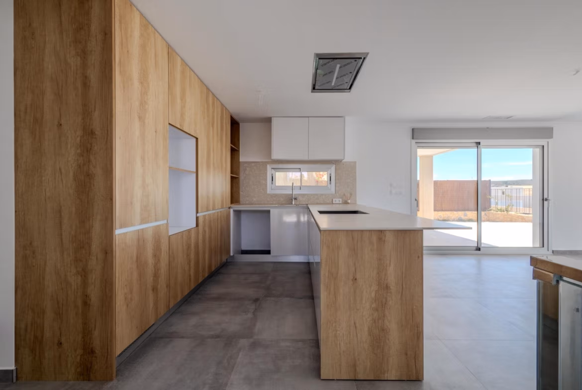 Modern sunlit kitchen with sleek wood cabinetry and open-plan layout in luxury 4-bedroom villa in Algorfa, La Finca.