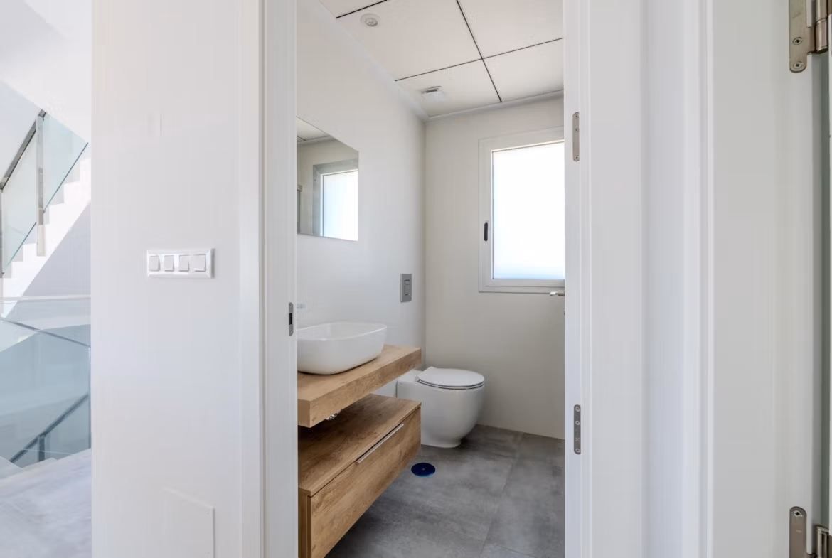 Bright, modern bathroom with sleek wood vanity and minimalist fixtures in a 4-bedroom villa in Algorfa, La Finca.