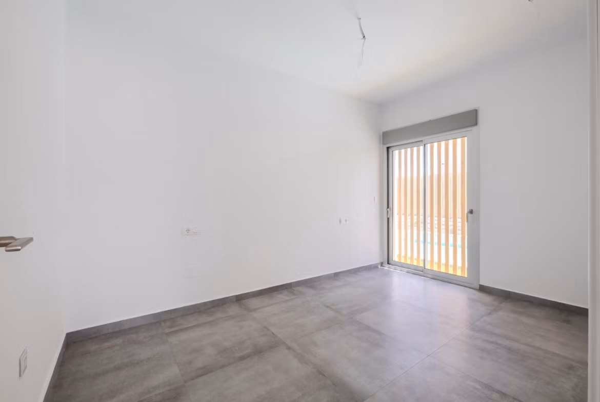 Bright, modern empty bedroom with large window and sleek tile flooring in 4-bedroom villa with golf views, Algorfa La Finca.