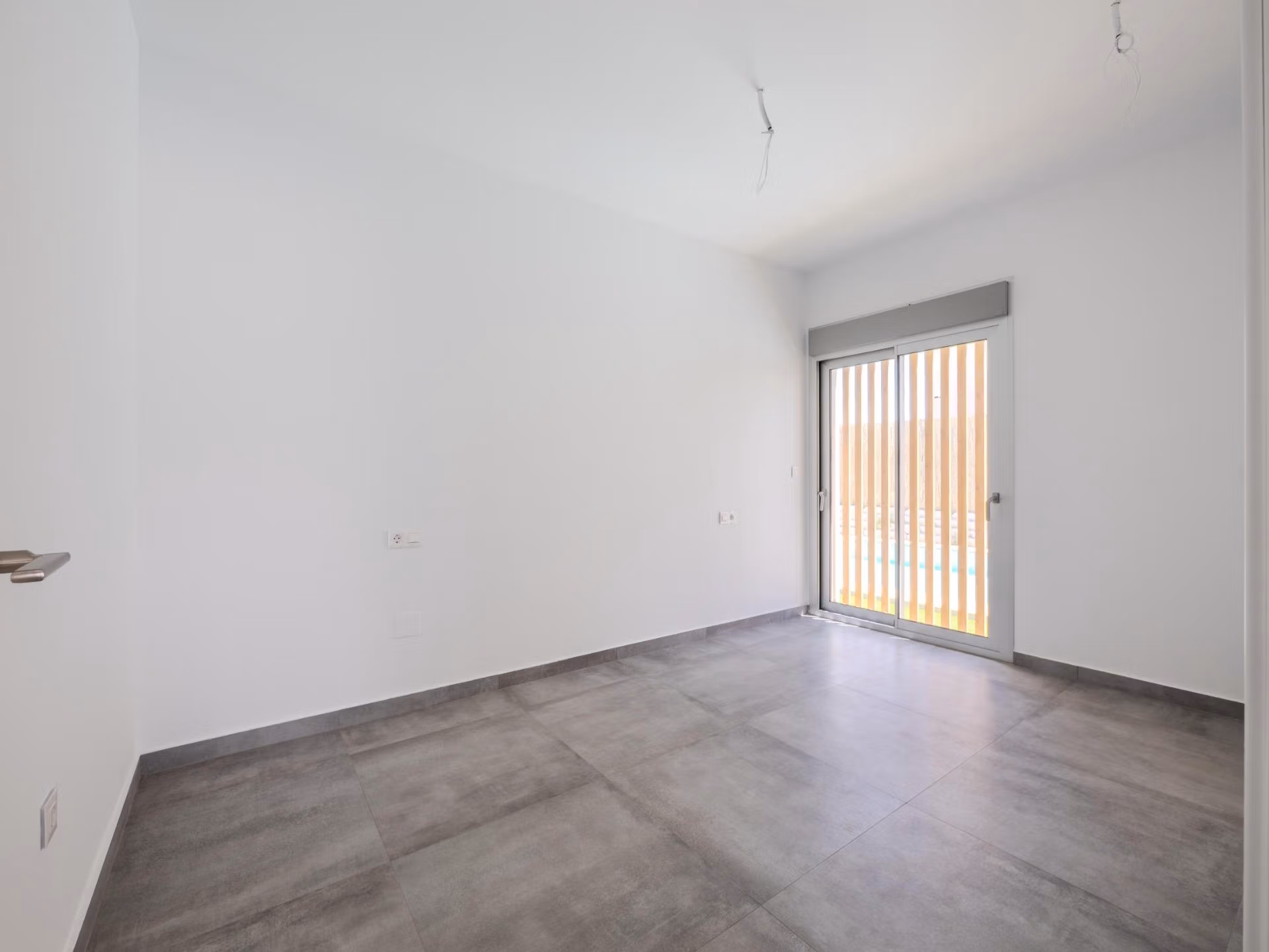 Bright, modern empty bedroom with large window and sleek tile flooring in 4-bedroom villa with golf views, Algorfa La Finca.
