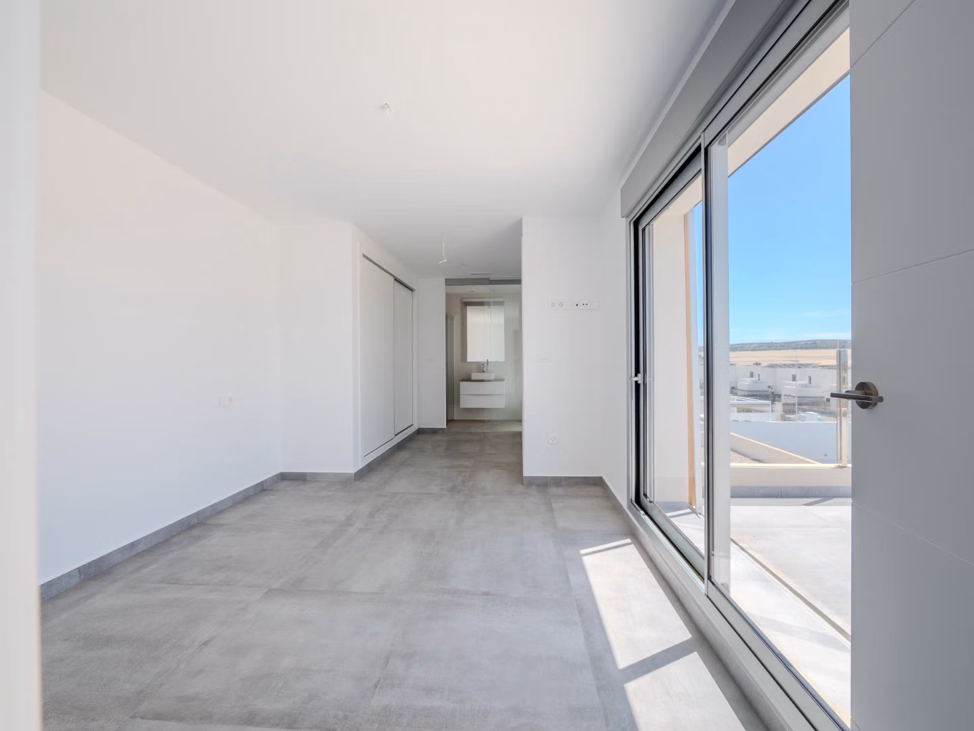 Bright, modern bedroom with sleek gray flooring and large sliding doors in a luxury 4-bedroom villa in Algorfa, La Finca.