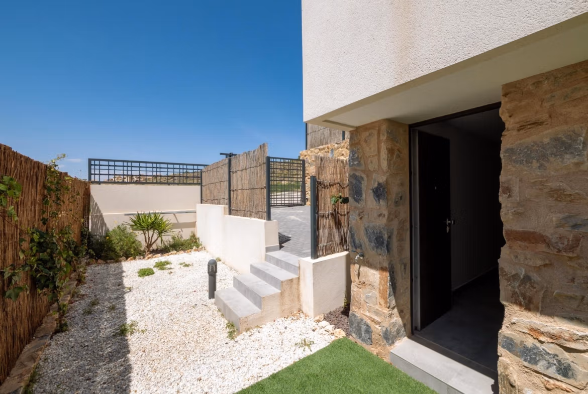 Sunny modern exterior corner of a key-ready 4-bedroom villa in Algorfa with stone accents and a private garden area.