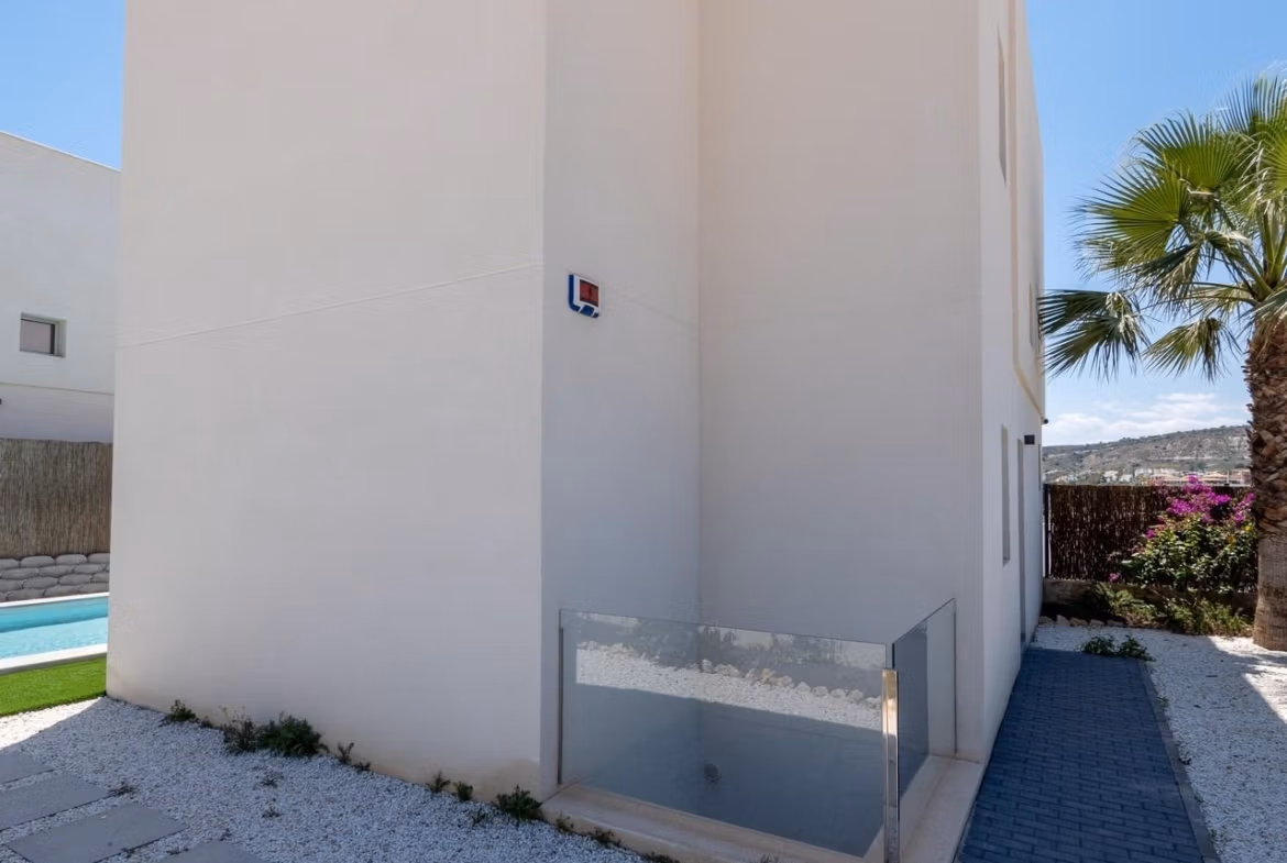 Modern exterior corner of luxury 4-bedroom villa in Algorfa with sleek pathway and glimpse of private pool and landscaped garden