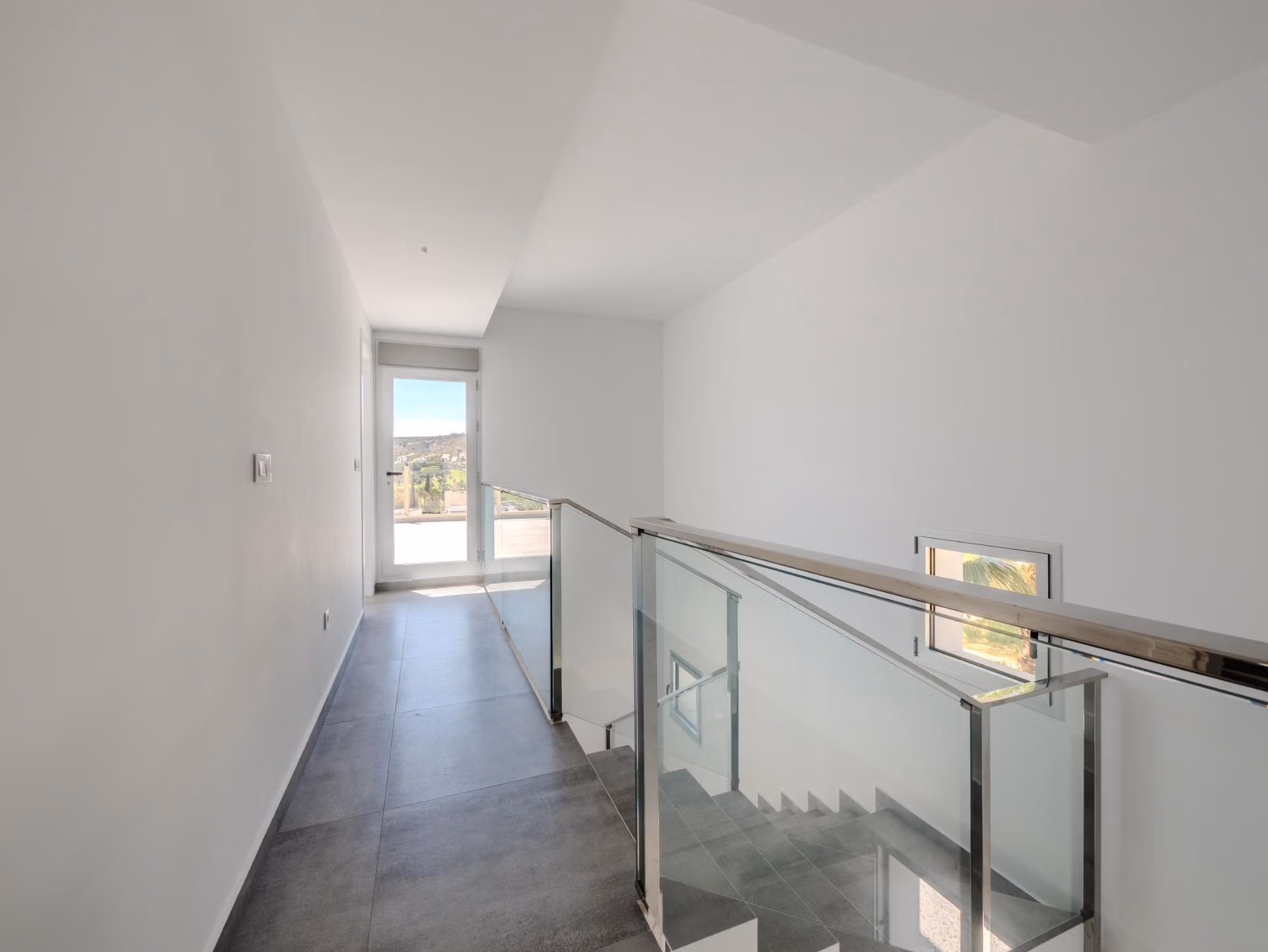 Bright modern hallway with sleek glass railing and natural light in luxury 4-bedroom villa with golf views in Algorfa, La Finca