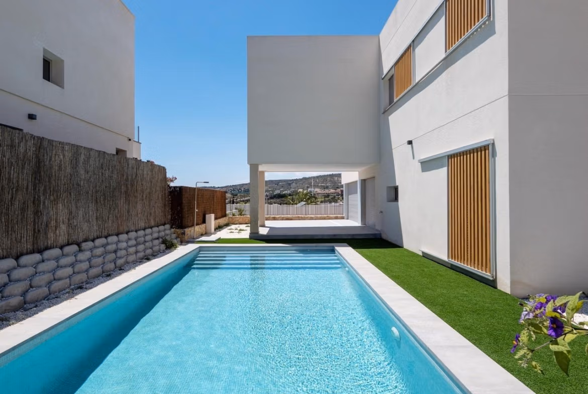 Sleek modern 4-bedroom villa in Algorfa with sparkling private pool and minimalist exterior under clear blue sky.