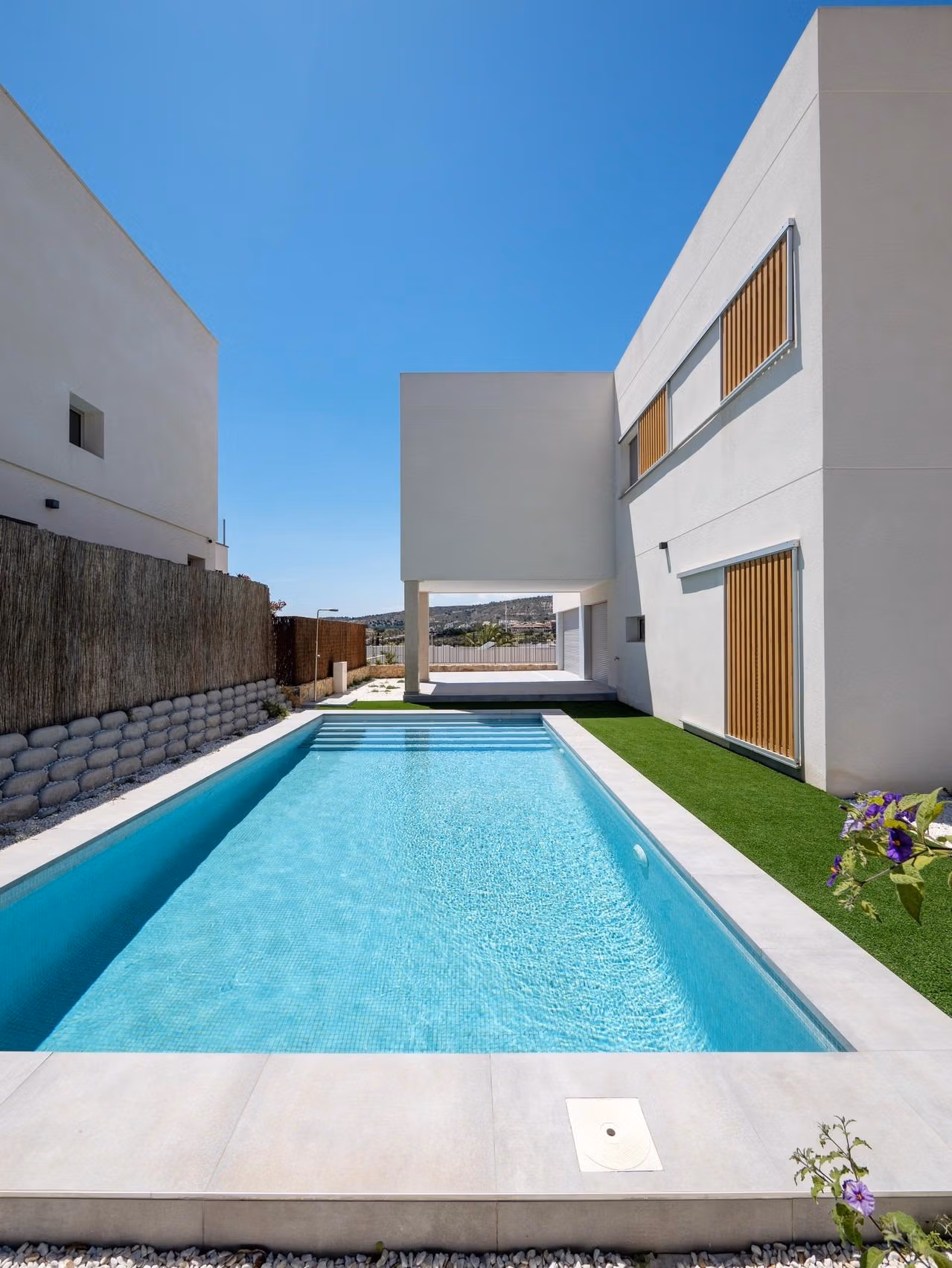 Sleek modern 4-bedroom villa in Algorfa with sparkling private pool and minimalist exterior under clear blue sky.