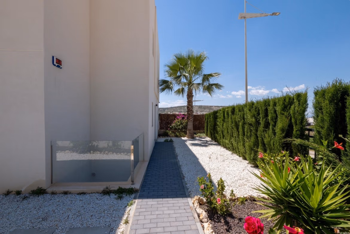 Elegant pathway with landscaped greenery and vibrant flowers beside a luxury 4-bedroom villa in Algorfa, La Finca with golf views.