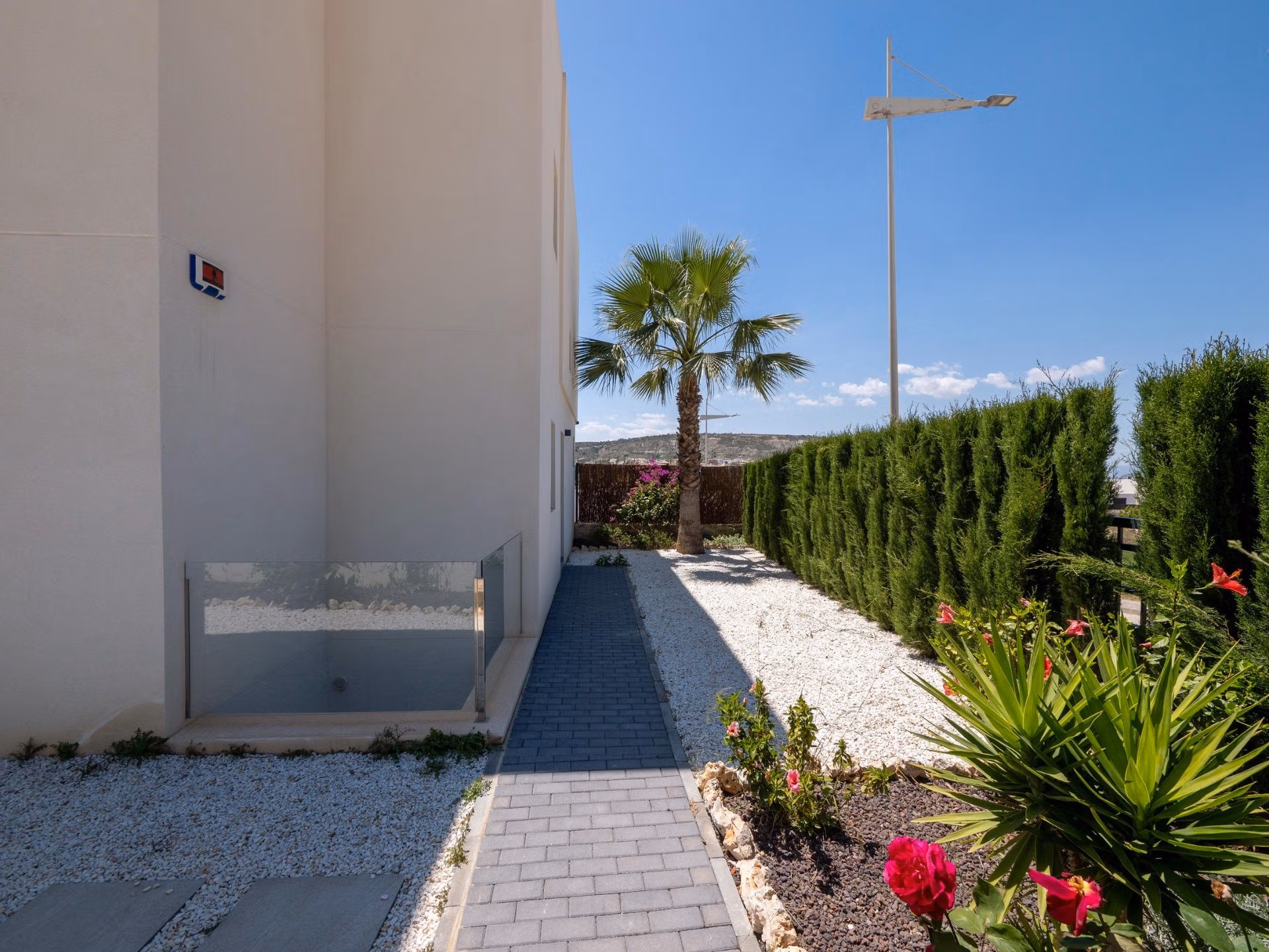 Elegant pathway with landscaped greenery and vibrant flowers beside a luxury 4-bedroom villa in Algorfa, La Finca with golf views.