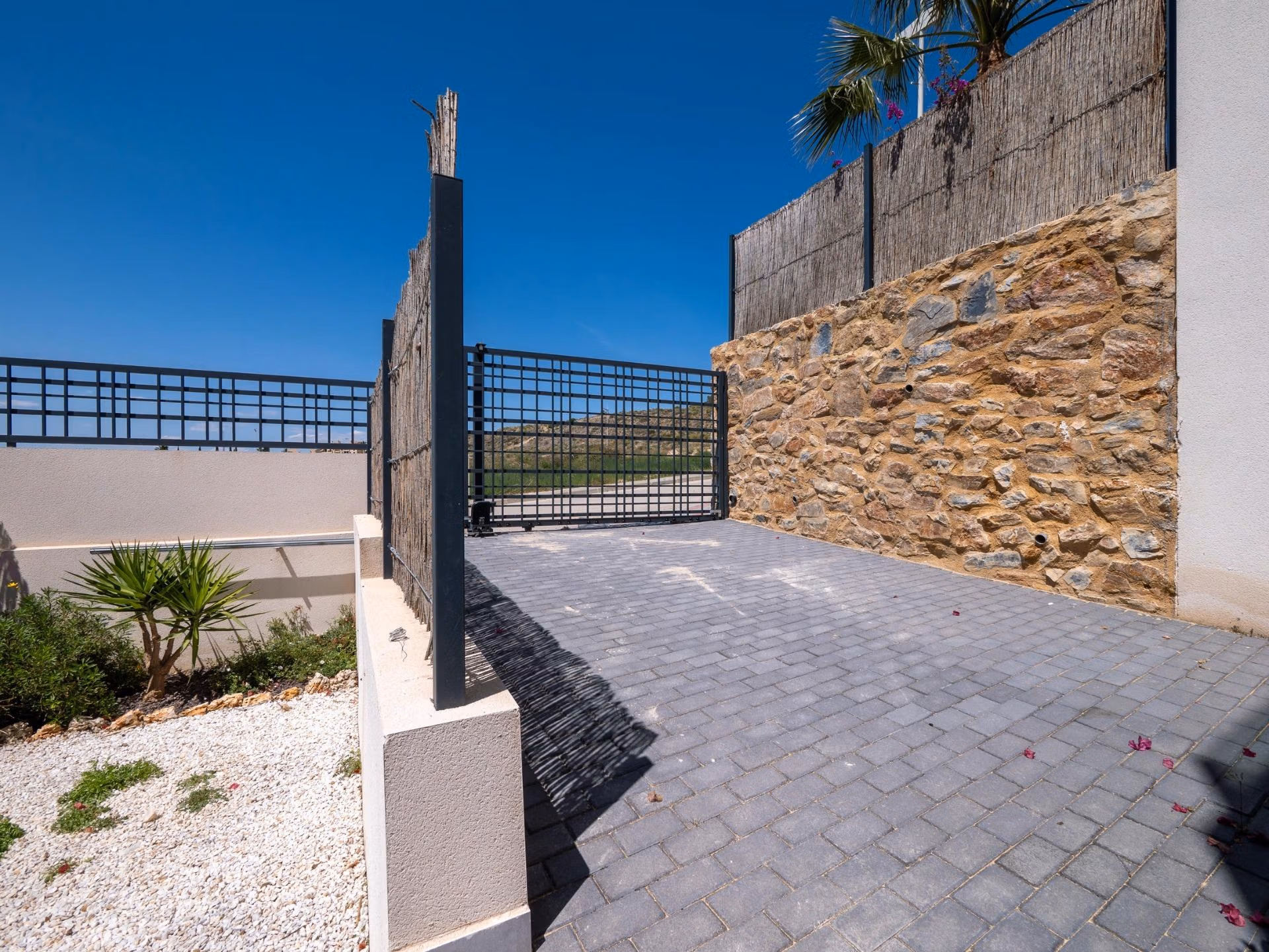 Private gated entrance with stone walls and modern driveway of a luxury 4-bedroom villa in Algorfa, La Finca golf views estate