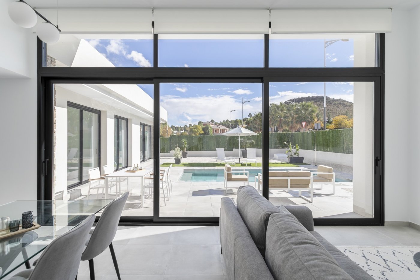 Bright open-plan living area with expansive glass doors overlooking a private pool and terrace in a modern 3-bedroom villa in Calasparra, Murcia.