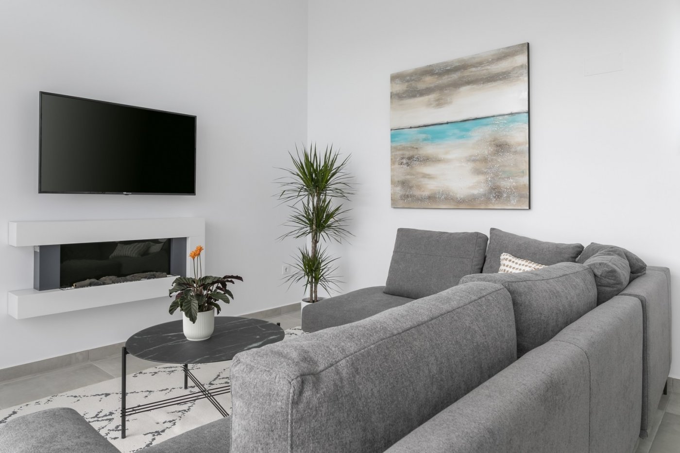 Modern bright living room with elegant grey sofa, contemporary fireplace, and coastal artwork in spacious 3-bedroom villa, Calasparra Murcia.
