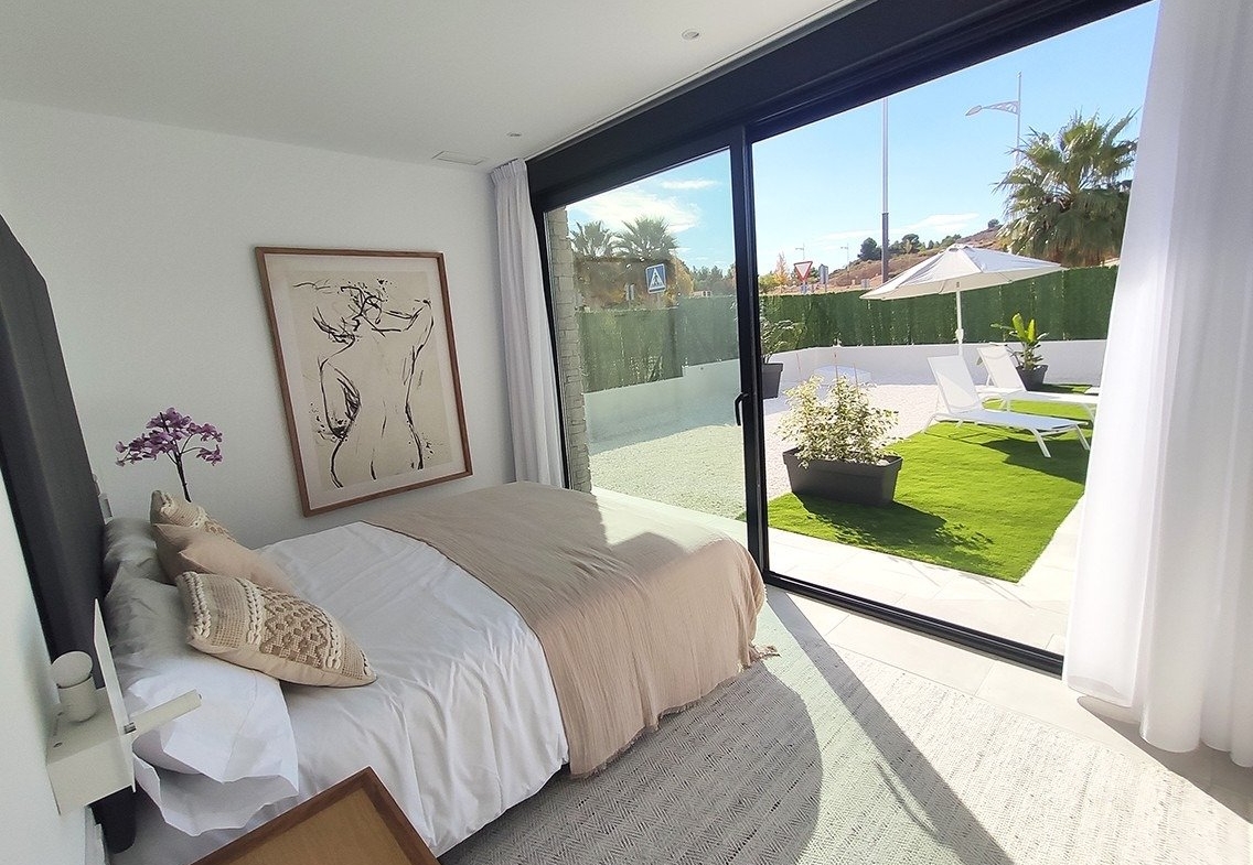 Bright and spacious bedroom with modern decor and sliding glass doors opening to a sunlit private terrace in a 3-bedroom villa in Calasparra, Murcia