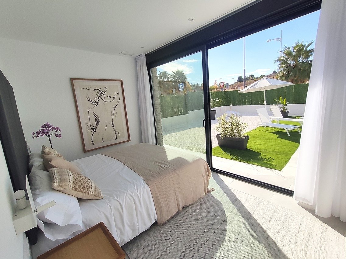Bright and spacious bedroom with modern decor and sliding glass doors opening to a sunlit private terrace in a 3-bedroom villa in Calasparra, Murcia
