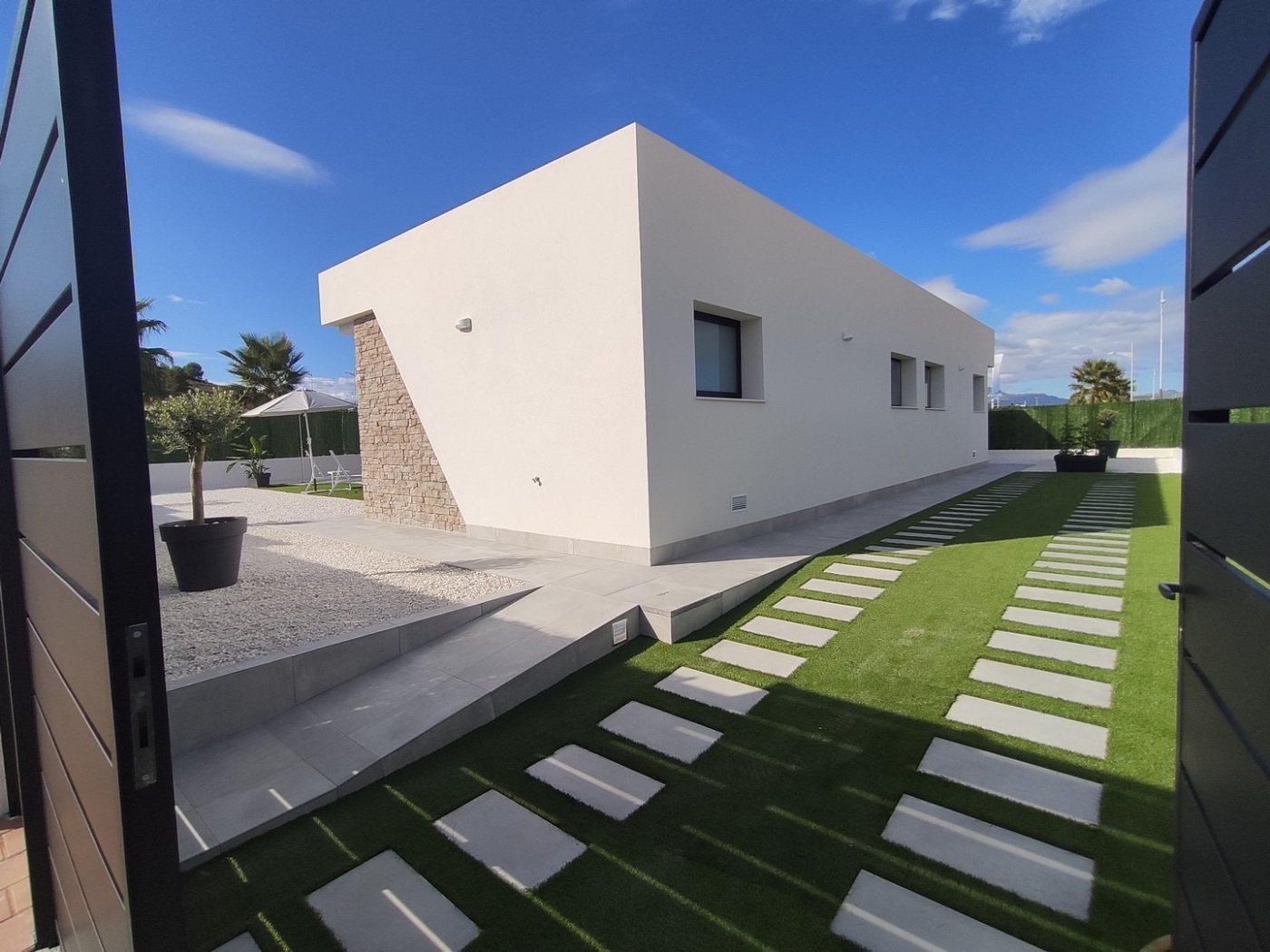 Sleek modern exterior of a spacious 3-bedroom villa with landscaped garden in Calasparra, Murcia, under clear blue skies.