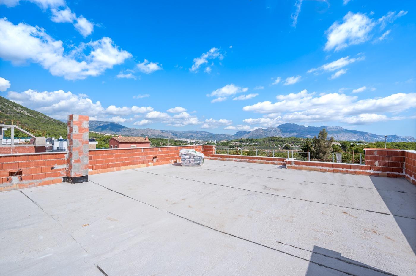 Spacious rooftop terrace of luxury 5-bedroom villa in Polop de la Marina with panoramic mountain and sea views under vibrant blue sky.
