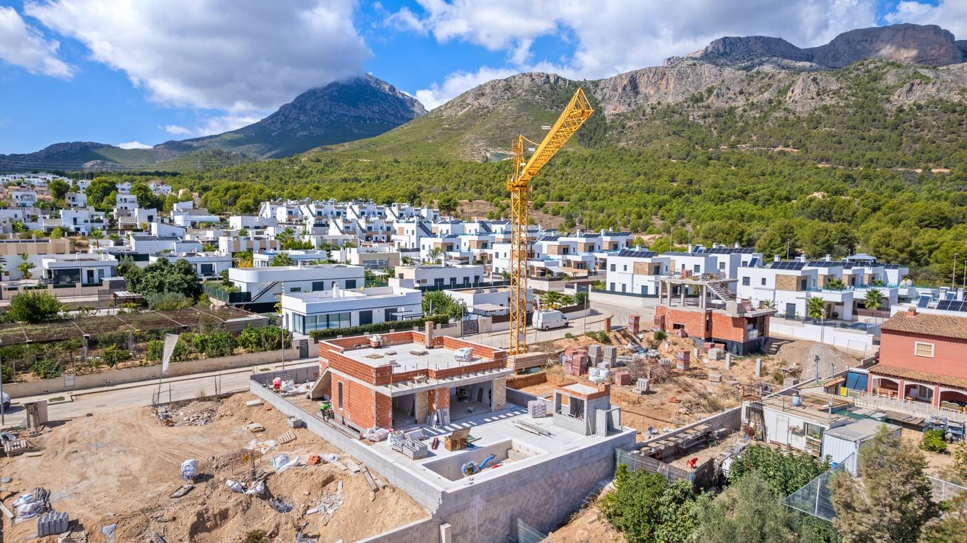 Expansive luxury 5-bedroom villa under construction in Polop de la Marina, set against dramatic mountain backdrop and lush greenery.