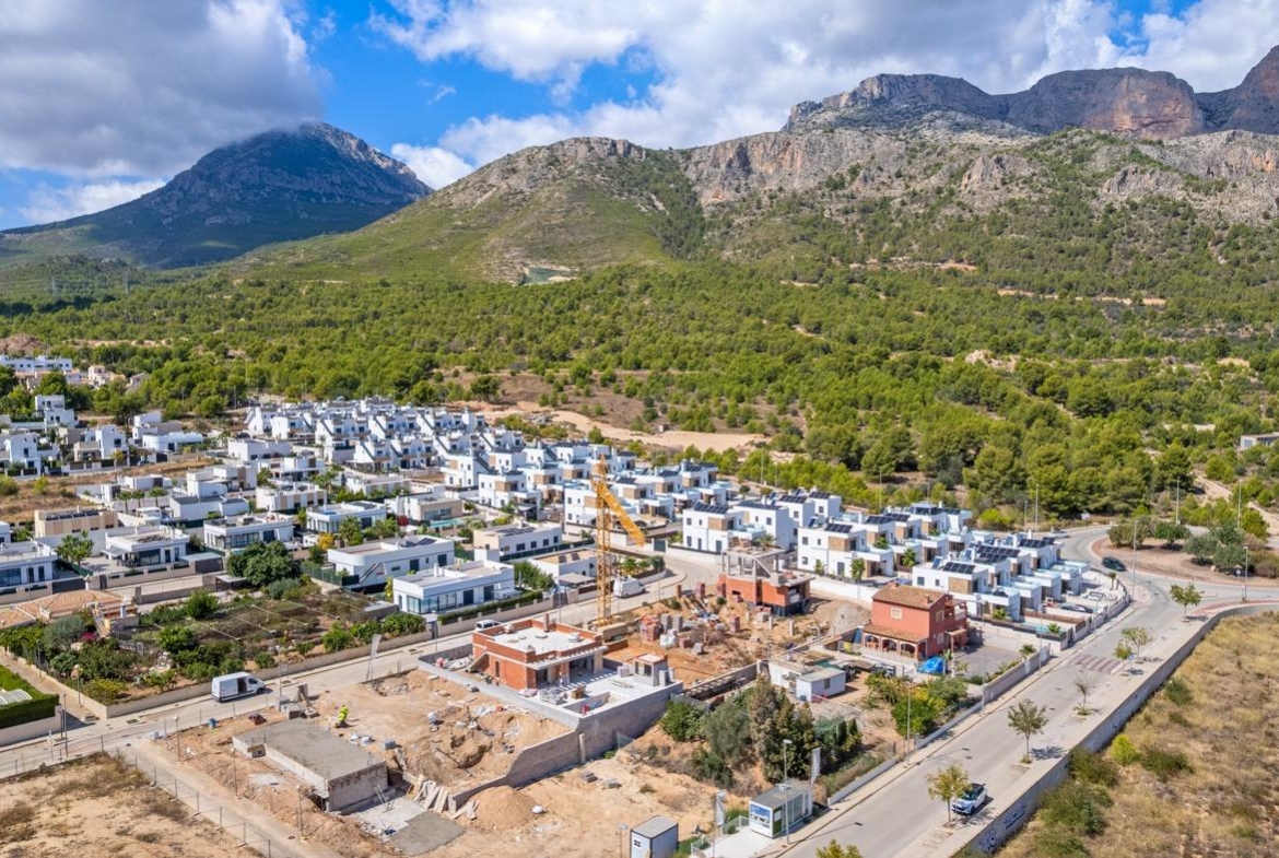 Expansive luxury 5-bedroom villa under construction amid modern homes with panoramic mountain views in Polop de la Marina.