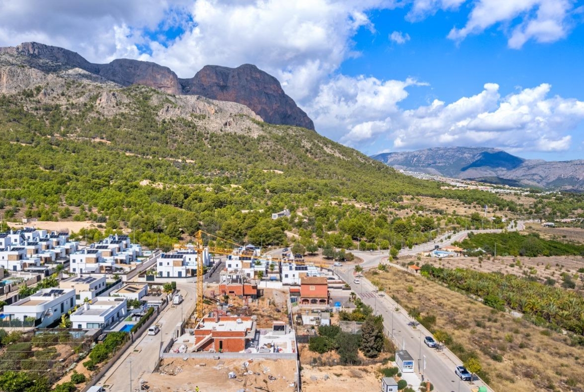 Panoramic view of Polop de la Marina showcasing mountain backdrop and surrounding modern luxury villas in a sunlit valley.