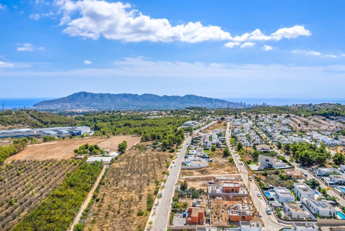 Panoramic aerial view of a spacious luxury 5-bedroom villa in Polop de la Marina with landscaped gardens and sea and mountain views.