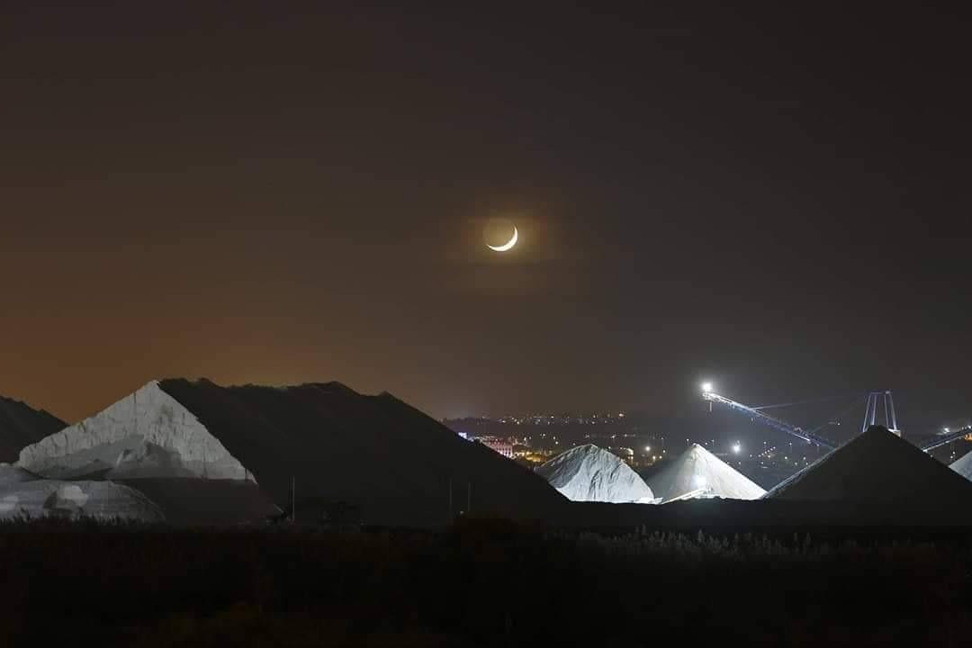 Night view of illuminated salt pyramids under a crescent moon near central Torrevieja, close to the sea and new luxury apartments.