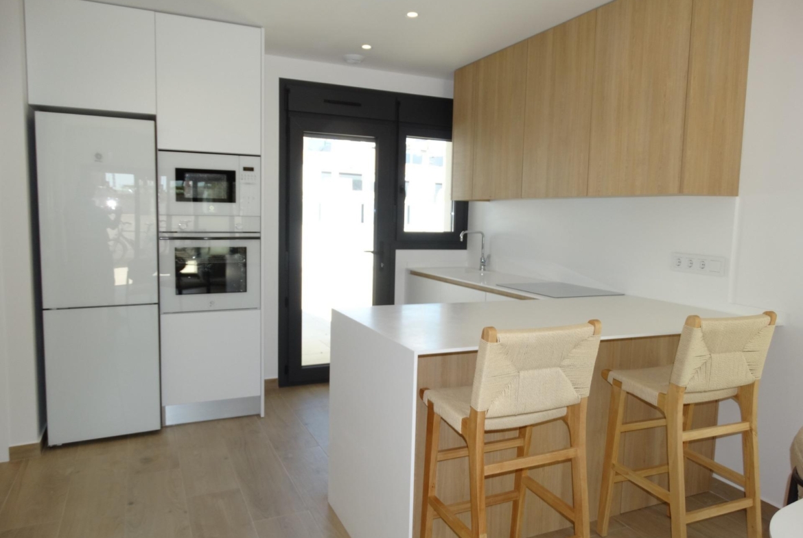 Modern-New-Build-Bungalows-for-Sale-in-Pilar-de-la-Horadada-11 Bright, modern kitchen with sleek white cabinetry and wooden accents in a new build bungalow in Pilar de la Horadada