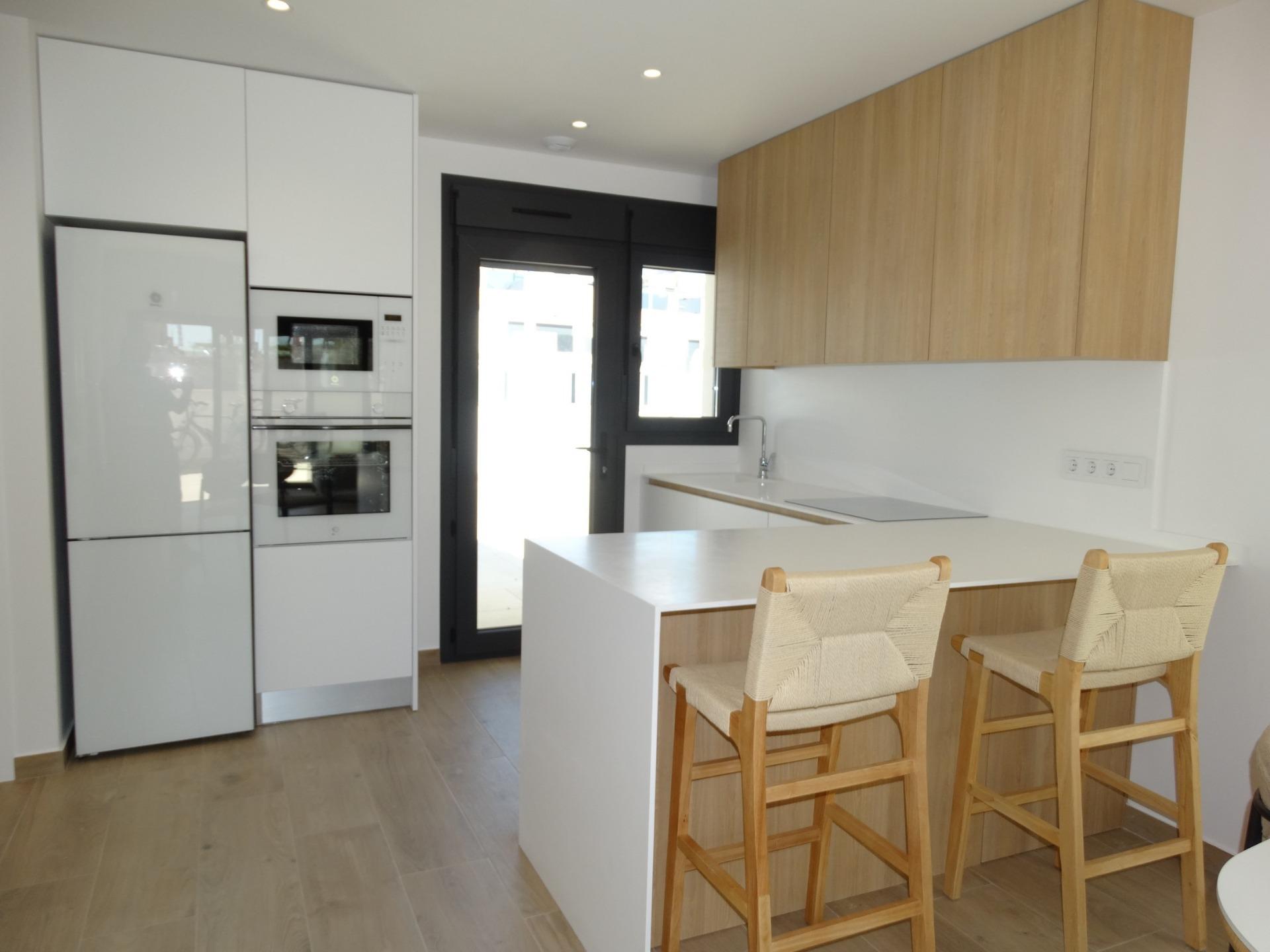 Modern-New-Build-Bungalows-for-Sale-in-Pilar-de-la-Horadada-11 Bright, modern kitchen with sleek white cabinetry and wooden accents in a new build bungalow in Pilar de la Horadada