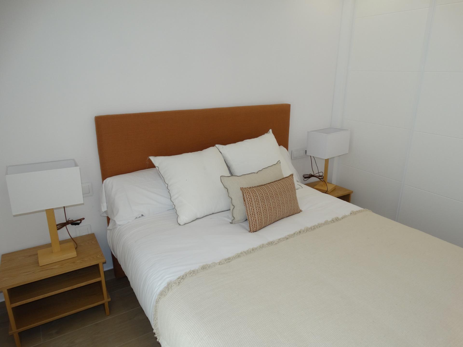 Bright, modern bedroom with elegant bedside lamps in a new build bungalow for sale in Pilar de la Horadada