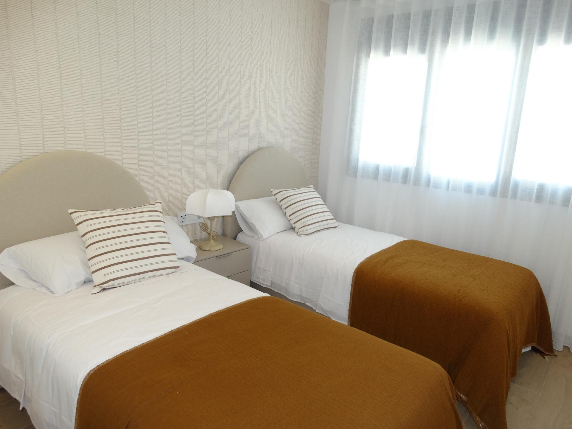 Modern-New-Build-Bungalows-for-Sale-in-Pilar-de-la-Horadada-15 Bright, modern twin bedroom with cozy bedding and soft natural light in luxury new build bungalows in Pilar de la Horadada
