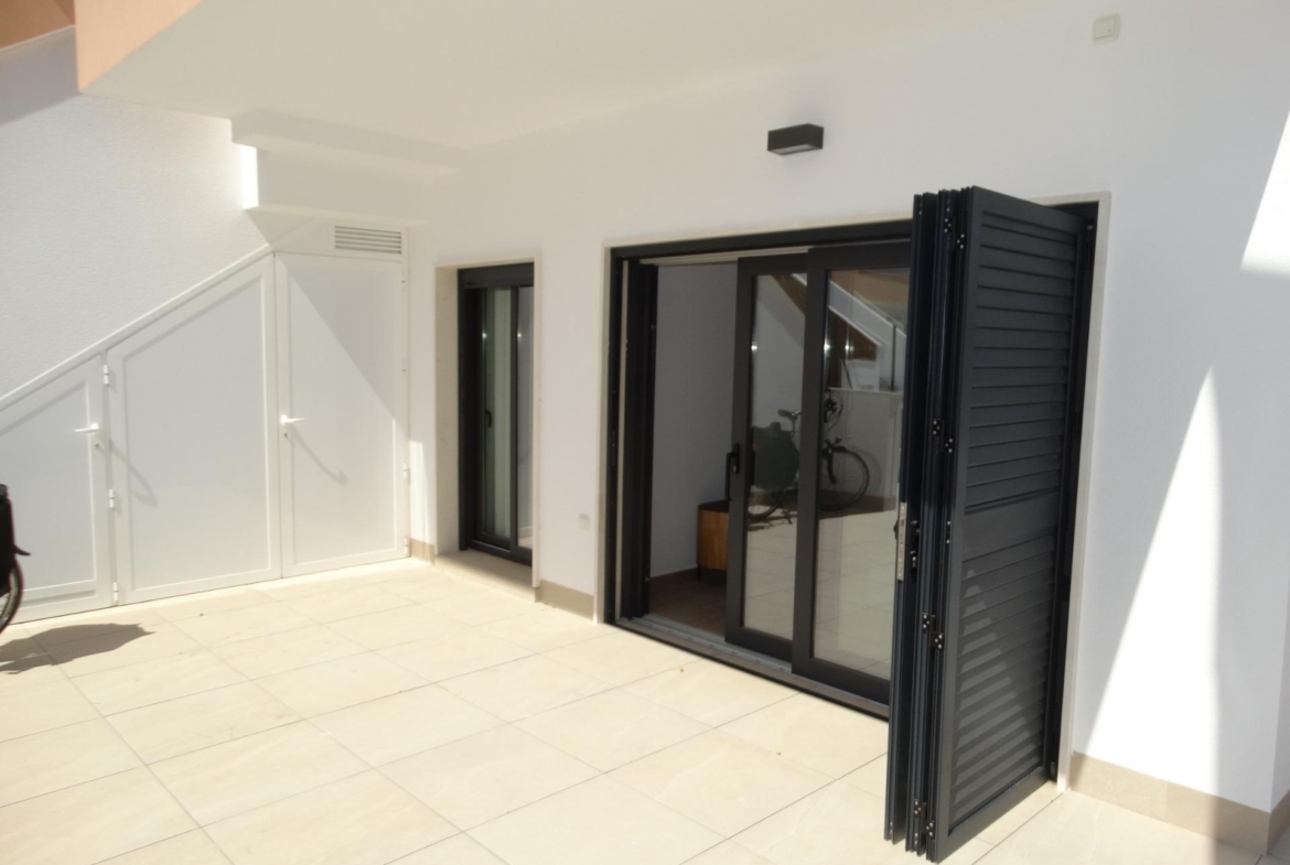 Sun-drenched modern terrace with sleek black shutters in a new build bungalow for sale in Pilar de la Horadada