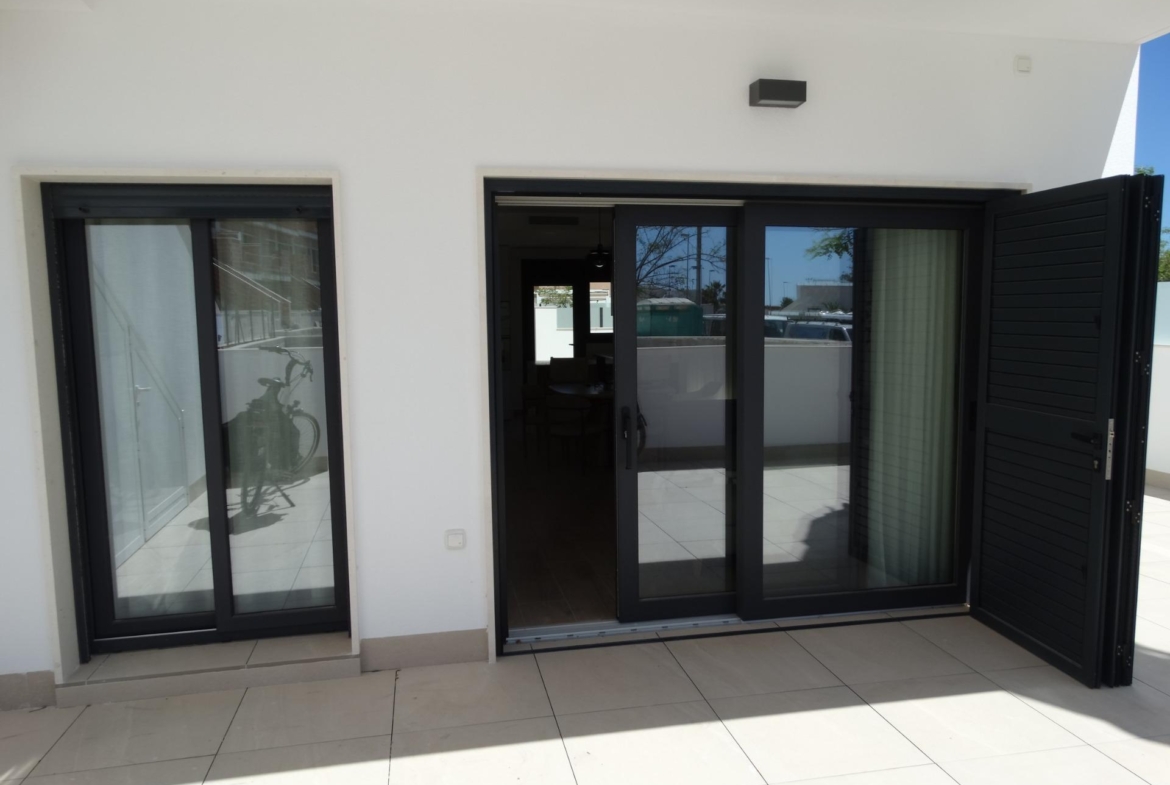 Bright modern terrace with sliding glass doors and shutters in luxury new build bungalows in Pilar de la Horadada.